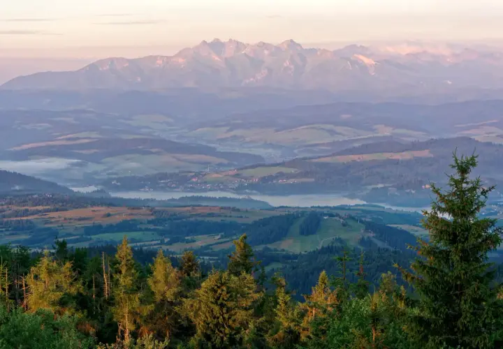 Widok z lubań szczyt na Tatry o wschodzie słońca. Mgły unoszą się nad doliną, a lasy i pola tworzą malowniczy krajobraz.