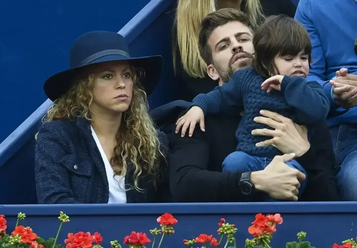 Shakira i Pique oglądają mecz, siedząc obok siebie. Pique trzyma na rękach dziecko.
