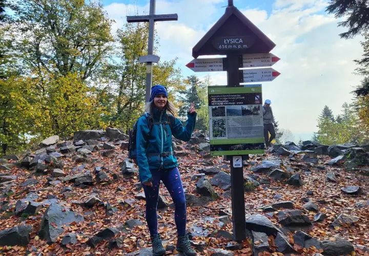 Kobieta na szczycie Łysicy, najwyższego szczytu Gór Świętokrzyskich. Jesienne liście i kamienie wokół.