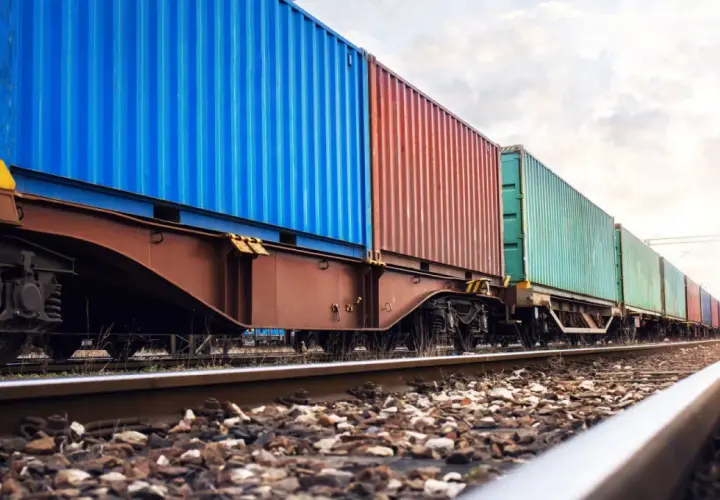 Długi pociąg towarowy z kolorowymi kontenerami na torach. To przykład transportu kolejowego, który jest kluczowy dla globalnej logistyki.