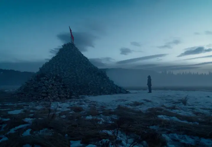 Un uomo solitario osserva un'enorme piramide di teschi in un paesaggio innevato. Un'immagine che evoca le recensioni de "The Revenant".