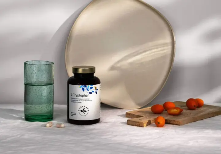 Flasche L-Tryptophan, die Vorstufe für Serotonin, neben Gläsern und Kumquats.