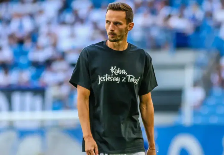 Rafał Wolski, komentator, na boisku w koszulce "Kuba, jesteśmy z Tobą!".