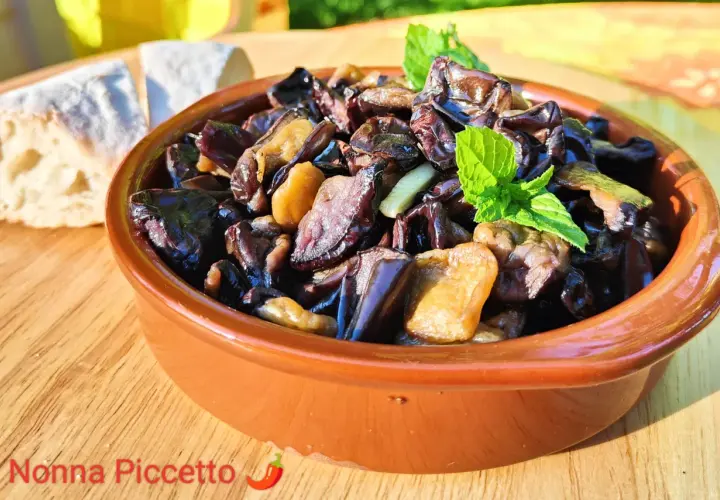 Melanzane alla scapece in terracotta, guarnite con menta fresca, accanto a pane casereccio. Un piatto estivo che profuma di tradizione.