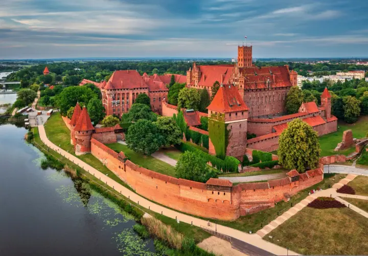 Ogromny zamek w Malborku, otoczony murami i fosą, zachwyca. Warto zobaczyć to cudo, opinie są jednoznaczne!