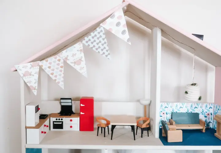 Uroczy domek dla lalek DIY z kuchnią, jadalnią i salonem. Girlanda z makaroników dodaje mu uroku.