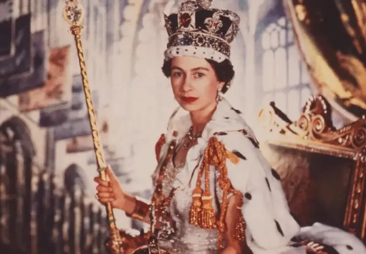 Elizabeth II av Storbritannien, krönt och med spira, sitter på tronen i sin kungliga dräkt.