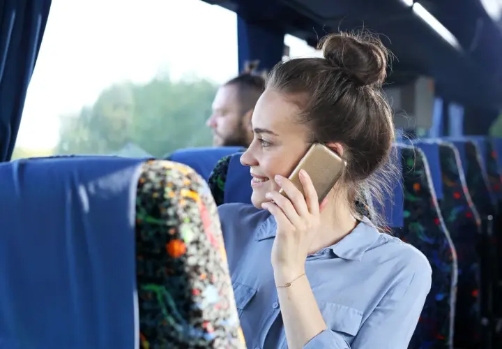 Kobieta w autobusie rozmawia przez telefon, zastanawiając się, jak włączyć roaming w Plus.