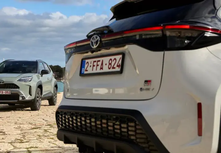 Dwa samochody Toyota, jeden biały, drugi zielony, stoją nad wodą. To świetny przykład, czym jest crossover – wszechstronny pojazd na każdą okazję.