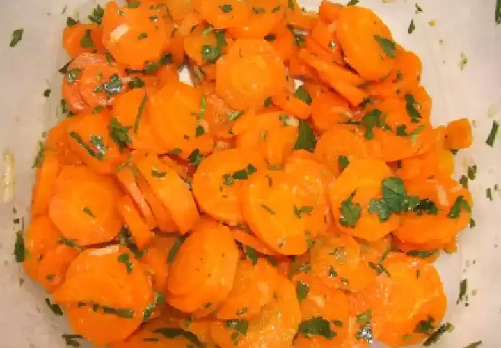 Una deliciosa ensalada de zanahoria cortada en rodajas finas y aderezada con perejil fresco.