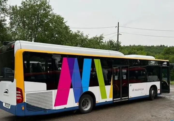 Autobus z kolorowym logo i napisem "Małopolska" na tle drzew.