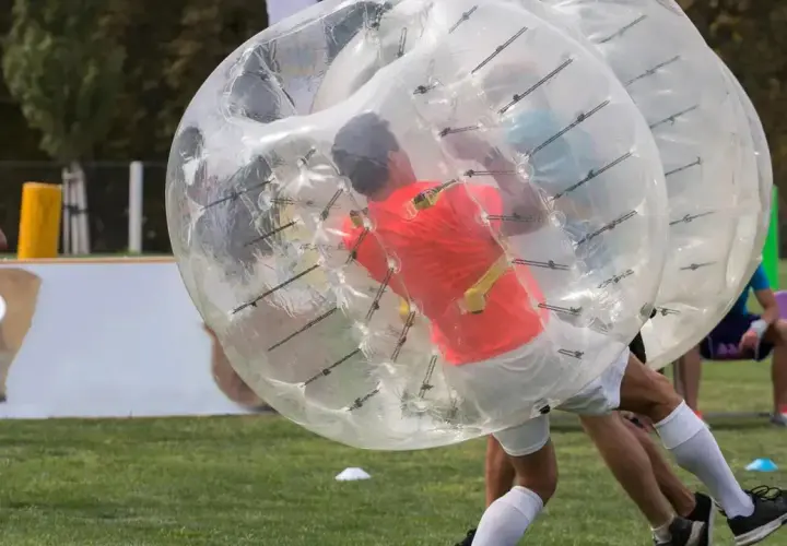 Gracze w wielkich, przezroczystych kulach zderzają się podczas gry w bubble football.