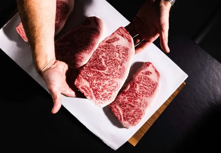 Des mains présentent des steaks de bœuf persillés, marbrés de gras, promettant le meilleur bœuf du monde.