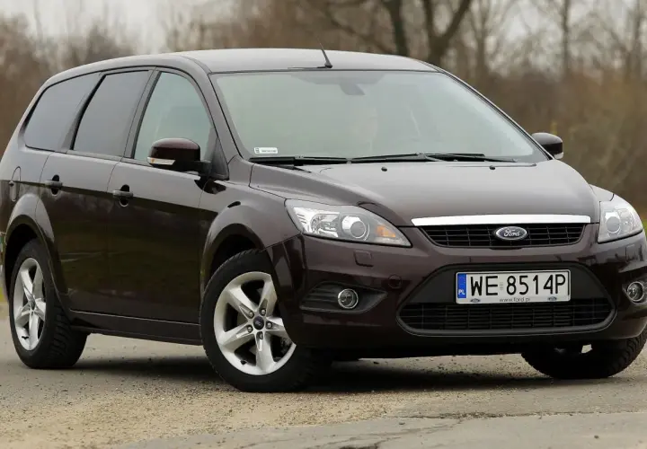 Ciemnobrązowy Ford Focus 2 kombi stoi na drodze.