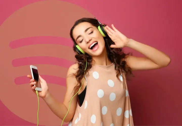 Dziewczyna z słuchawkami na uszach i telefonem w dłoni, ciesząca się muzyką. Idealna okazja, by sprawdzić Spotify Premium za 0,99!