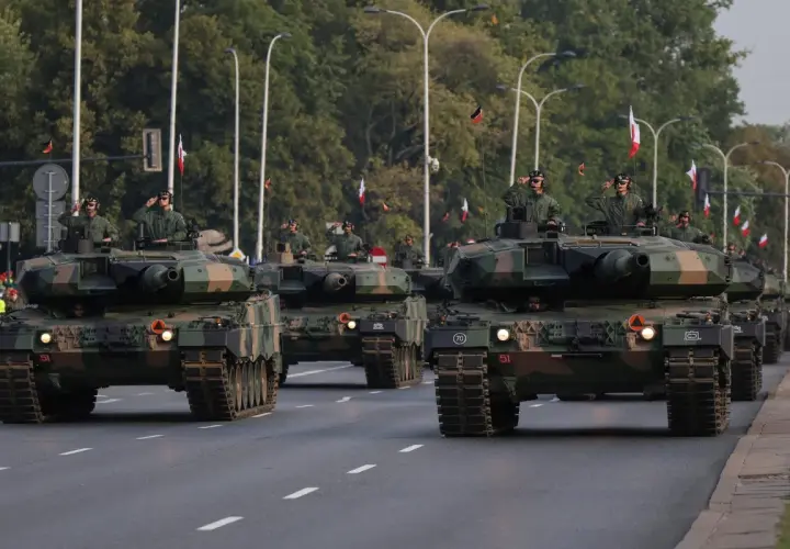 Parada wojskowa z nowoczesnym uzbrojeniem. Czołgi Leopard 2 maszerują ulicą, żołnierze pozdrawiają.