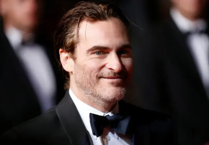 Joaquin Phoenix, który grał Jokera w filmie Joker, w czarnym smokingu i muszce.