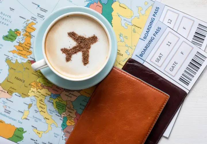 Une tasse de café avec un avion en cacao sur une carte du monde, à côté de billets d'avion. L'idée d'un voyage, d'une carte pass et étape.