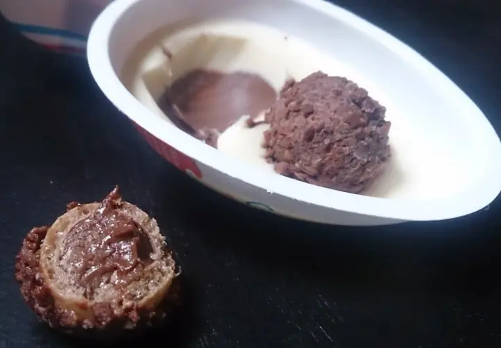 Lody Kinder Joy w białym opakowaniu z czekoladową kulką i kawałkiem waflowym z kremem.