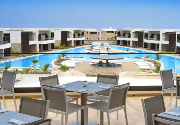 Luksusowy resort Royal Horizon Ponta Sino z basenem i barem. Stoły na tarasie czekają na gości.