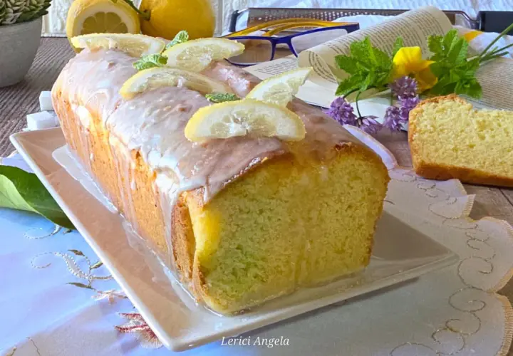 Un delizioso plumcake al limone glassato, decorato con fette di limone e menta, pronto per essere gustato.