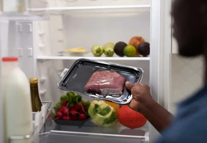 Un homme regarde un morceau de viande dans son emballage. Il se demande : viande hors frigo combien de temps ?