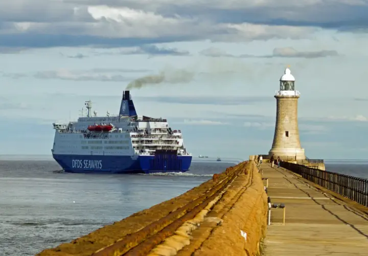 Duży prom DFDS Seaways wypływa z portu, kierując się na Bornholm. Obok stoi latarnia morska.