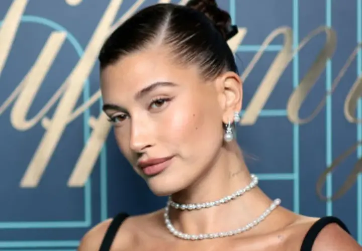 Elegancka kobieta z gładkim kokiem, w perłowej biżuterii, prezentuje klasyczny styl.