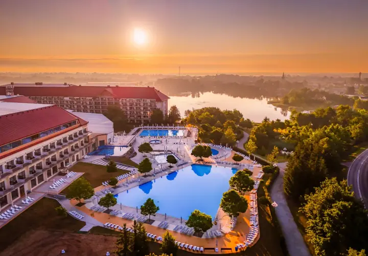 Hotel Gołębiewski Mikołajki o wschodzie słońca. Widok na rozległy kompleks basenów i jezioro.