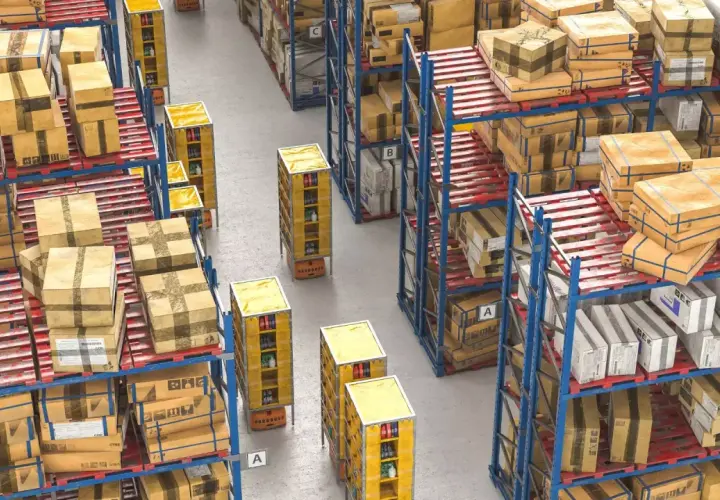 Duże magazynowe zapasy towarów na regałach i paletach. Automatyczne wózki transportują towary między rzędami.