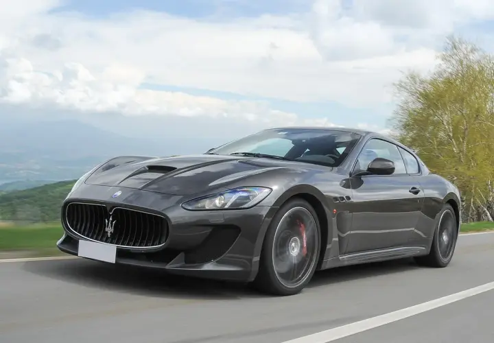Szary Maserati GranTurismo na krętej drodze. Marzysz o takim aucie? Sprawdź aktualną maserati cena!
