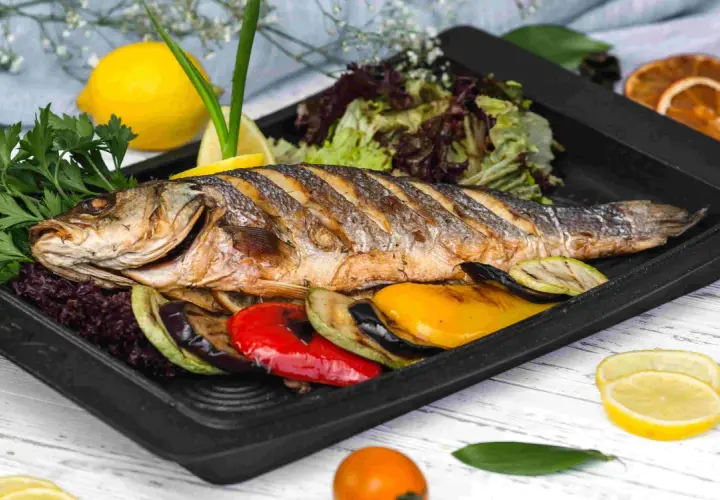 Apetyczna ryba z piekarnika z warzywami: grillowany bakłażan, cukinia, papryka, podana z sałatką i cytryną.