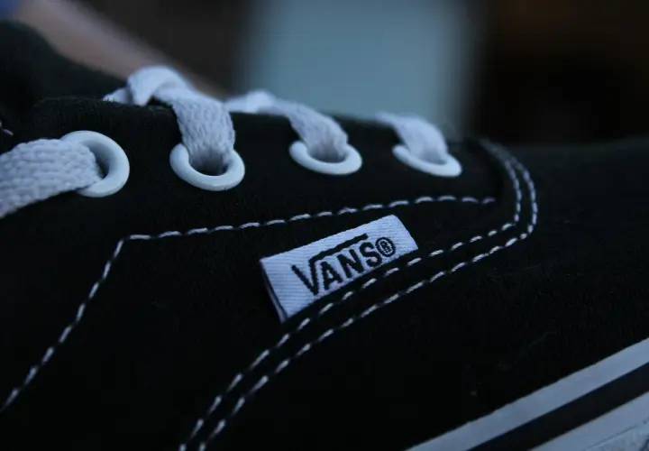 Zbliżenie na czarną tkaninę buta Vans z białymi sznurówkami i charakterystyczną metką.