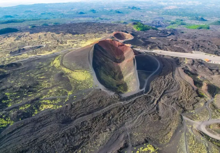 Vista aerea dei crateri spenti del vulcano Etna, con sentieri che si snodano tra la lava nera e la vegetazione gialla. Un'emozionante visita al Monte Etna.