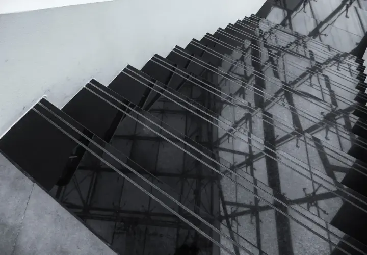 Ciemne schody z polerowanego konglomeratu odbijają architektoniczne detale, tworząc geometryczne wzory.
