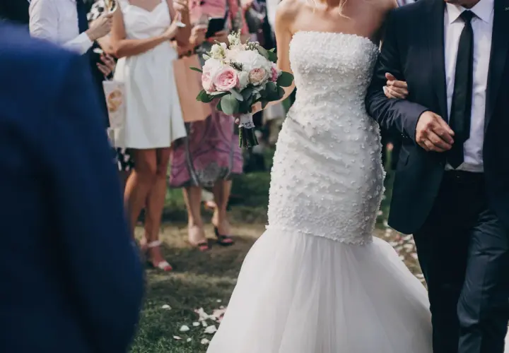Przepiękna suknia ślubna rybka, niczym syrena, podkreśla sylwetkę panny młodej. Bukiet róż i piwonii dopełnia jej ślubny look.