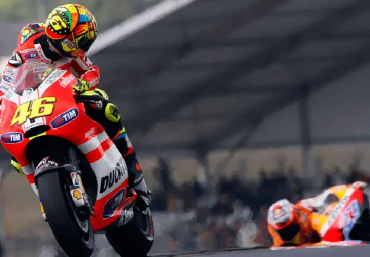 Valentino Rossi en su Ducati, número 46, inclinado en una curva. Otro piloto yace en el suelo.
