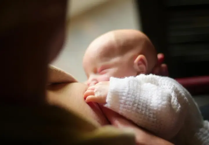 Un neonato dorme serenamente mentre viene allattato. Un momento intimo che fa riflettere su cosa mangiare in allattamento per il benessere di entrambi.