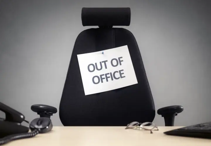 Puste biurowe krzesło z kartką "OUT OF OFFICE". Czas na zasłużone święta w sierpniu!