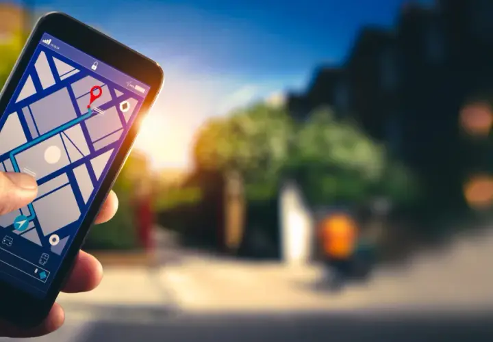 Dłoń trzyma smartfon z mapą i trasą. Dowiedz się, jak włączyć nawigację w telefonie, by łatwo dotrzeć do celu.