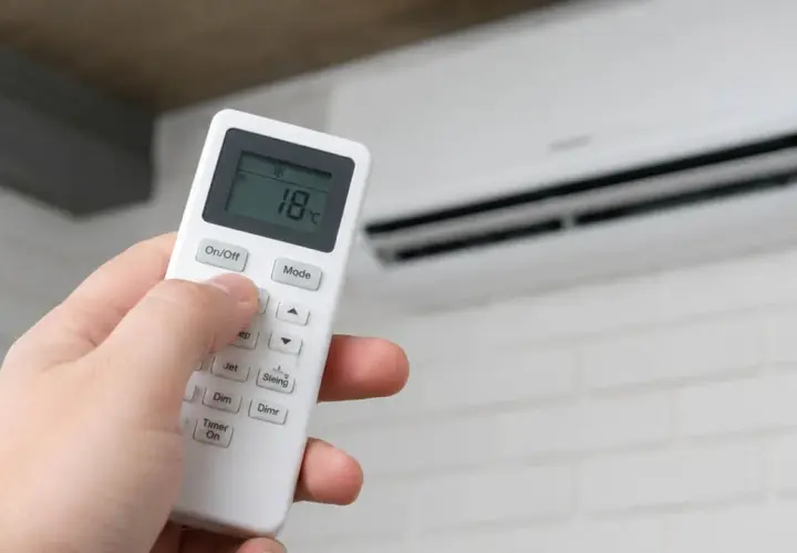 Mano ajustando el control remoto del aire acondicionado para un boost de aire fresco a 18°C.
