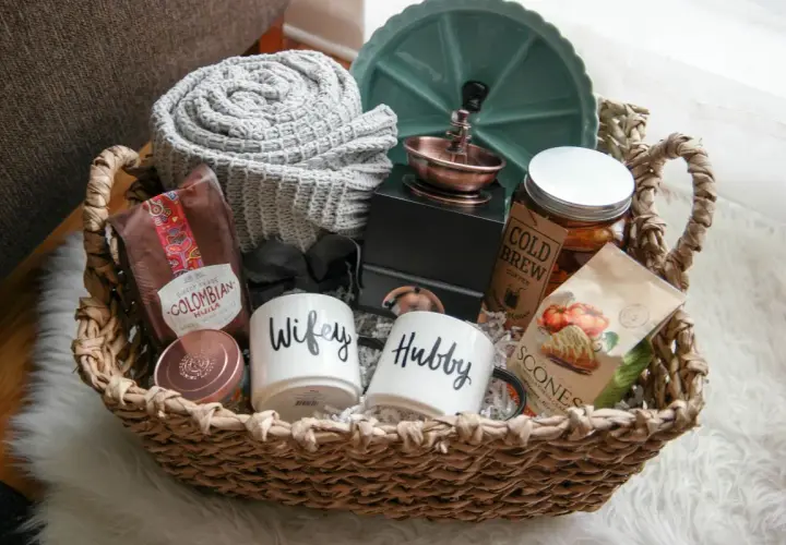 Cesta de mimbre con un kit para recién casados: tazas "Wifey" y "Hubby", café colombiano, scones, manta y más.