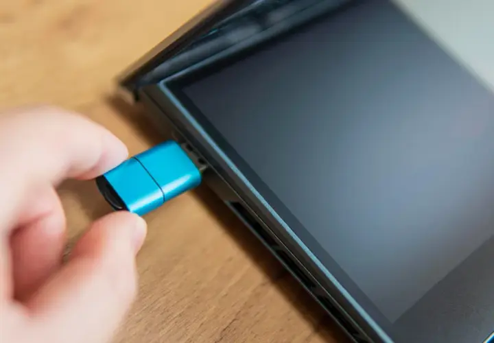 Dłoń podłącza niebieski pendrive do iPada. Dowiedz się, jak podłączyć pendrive do iPada, aby łatwo przenosić pliki.