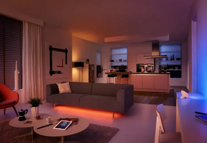Sofá moderno con iluminación led ambiental. Cocina integrada, arte abstracto y silla naranja. Las led caracteristicas crean una atmósfera acogedora.