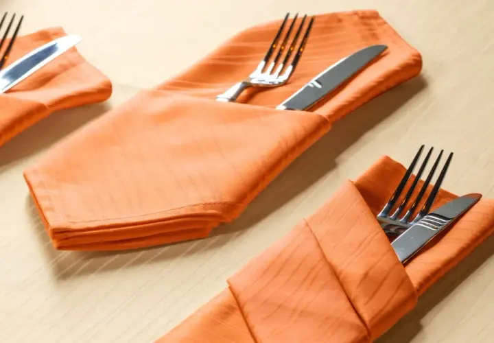 Orange Stoffservietten mit bestercktasche falten papier vorlage. Gedeckter Tisch für ein Festessen.