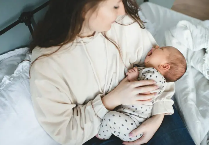 Mama tuli do synka, który właśnie zaczął wymioty u niemowlaka. Dziecko z otwartą buzią, mama tuli go czule.