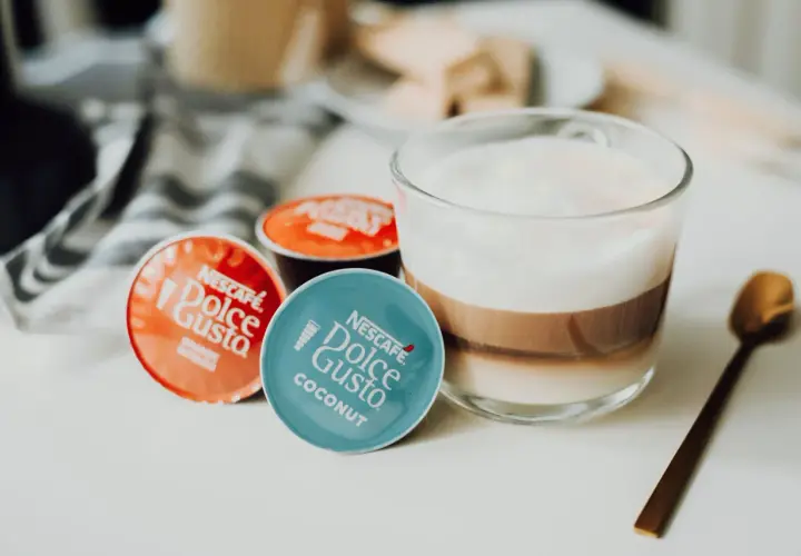 Kapsułki Dolce Gusto obok kawy z mlekiem. Może ekspres Dolce Gusto nie chce wyjąć kapsułki?