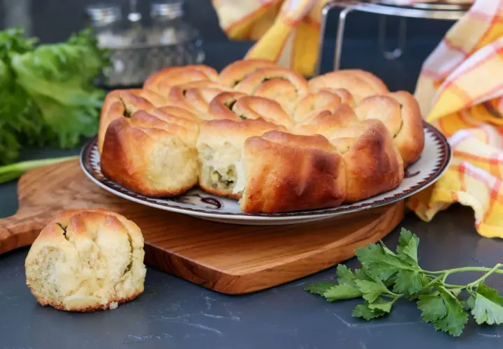 Puszysty chlebek ziołowy z Thermomixa, upieczony na złoto, z zieloną natką pietruszki obok.