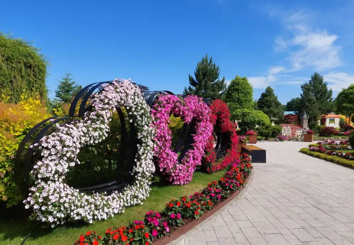 Trzy serca z kwiatów: białe, różowe i czerwone, ozdabiają park podczas festiwalu kwiatów.