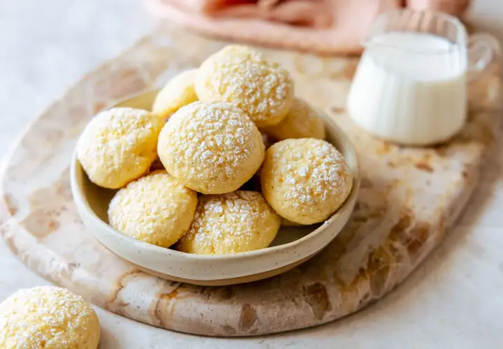 Biscotti da inzuppo soffici e dorati, cosparsi di zucchero a velo, pronti per essere gustati con un bicchiere di latte.